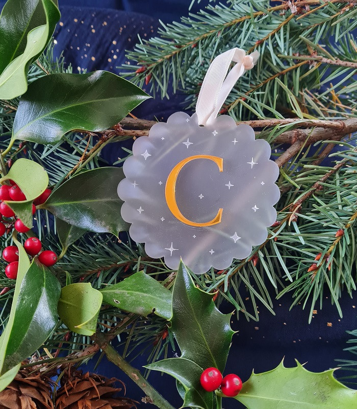 Boule de Noël ronde en plexi givré avec initiale acrylique rouge personnalisable, effet gelé et étoiles gravées.